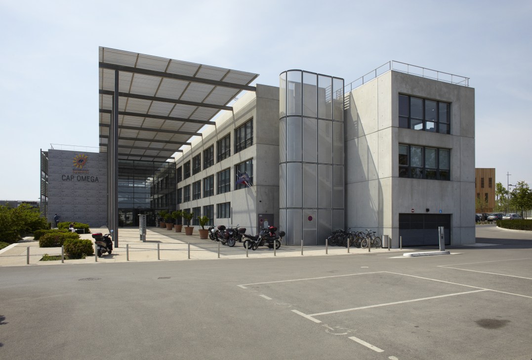 Modern Business Innovation Centre building with glass and concrete facade, bikes parked outside, clear sky.