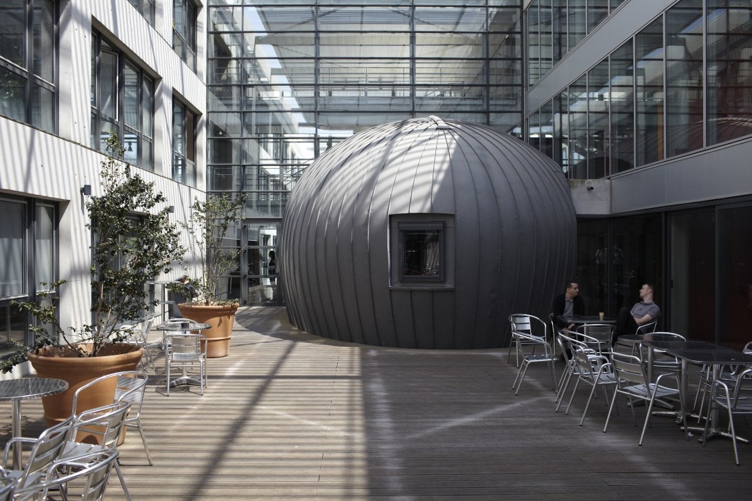 Inner courtyard at the Business Innovation Centre with a distinctive black dome structure and modern glass buildings surrounding a patio with seating.
