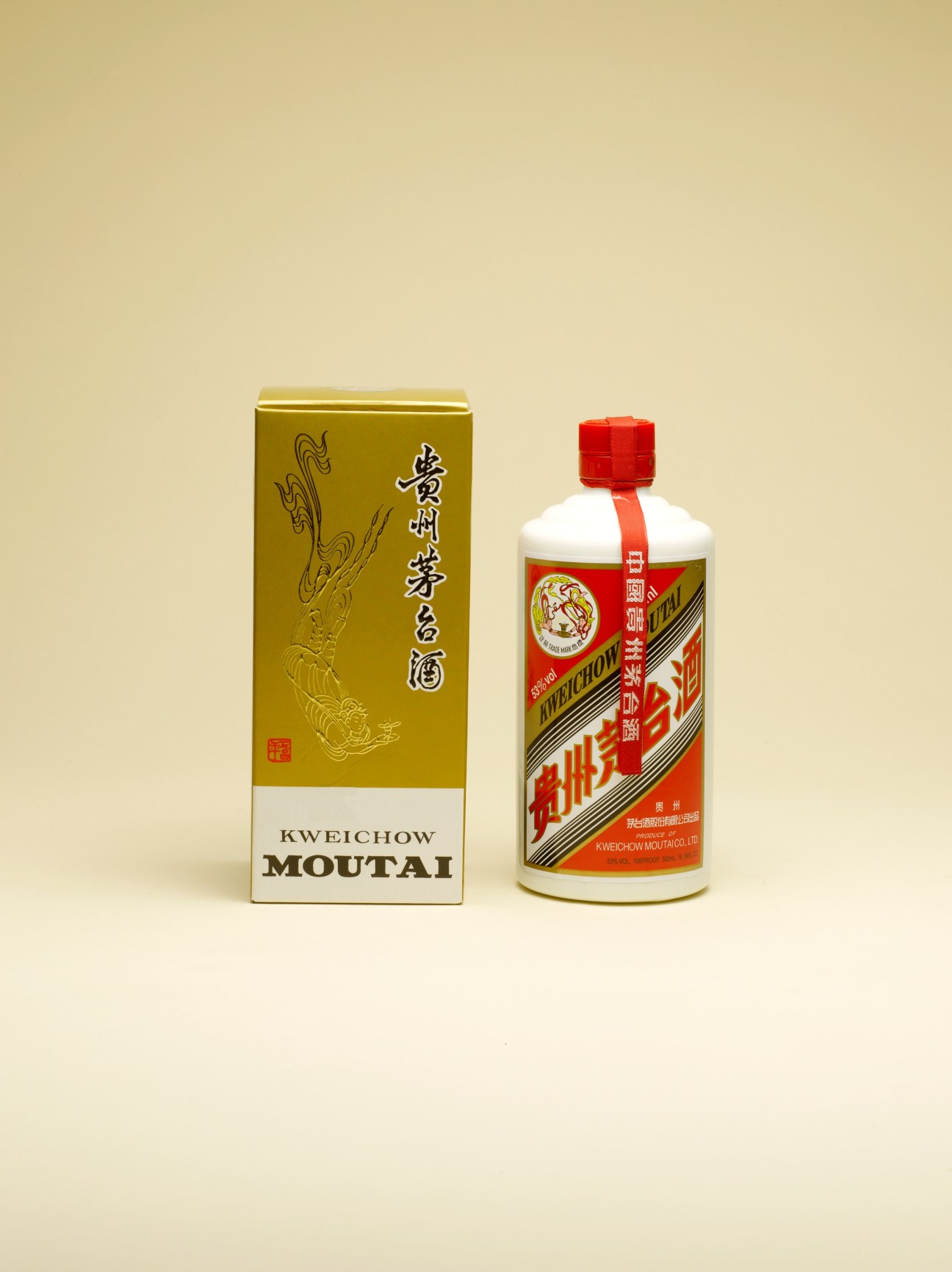 Moutai bai jiu bottle with gold box and white porcelain bottle with red cap and label against beige background.