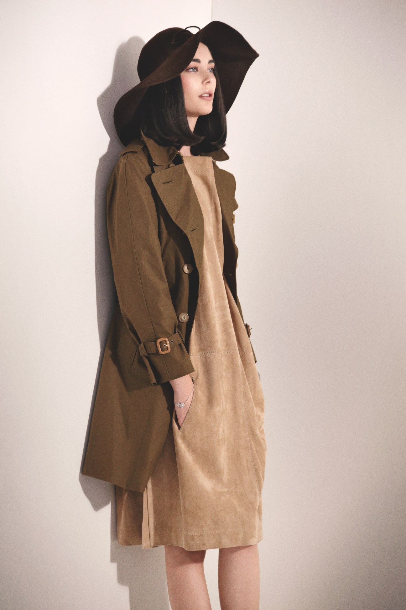 Model wearing a black wide-brimmed hat, Mackintosh coat in brown, Hermès dress in camel, and Chanel bracelet.