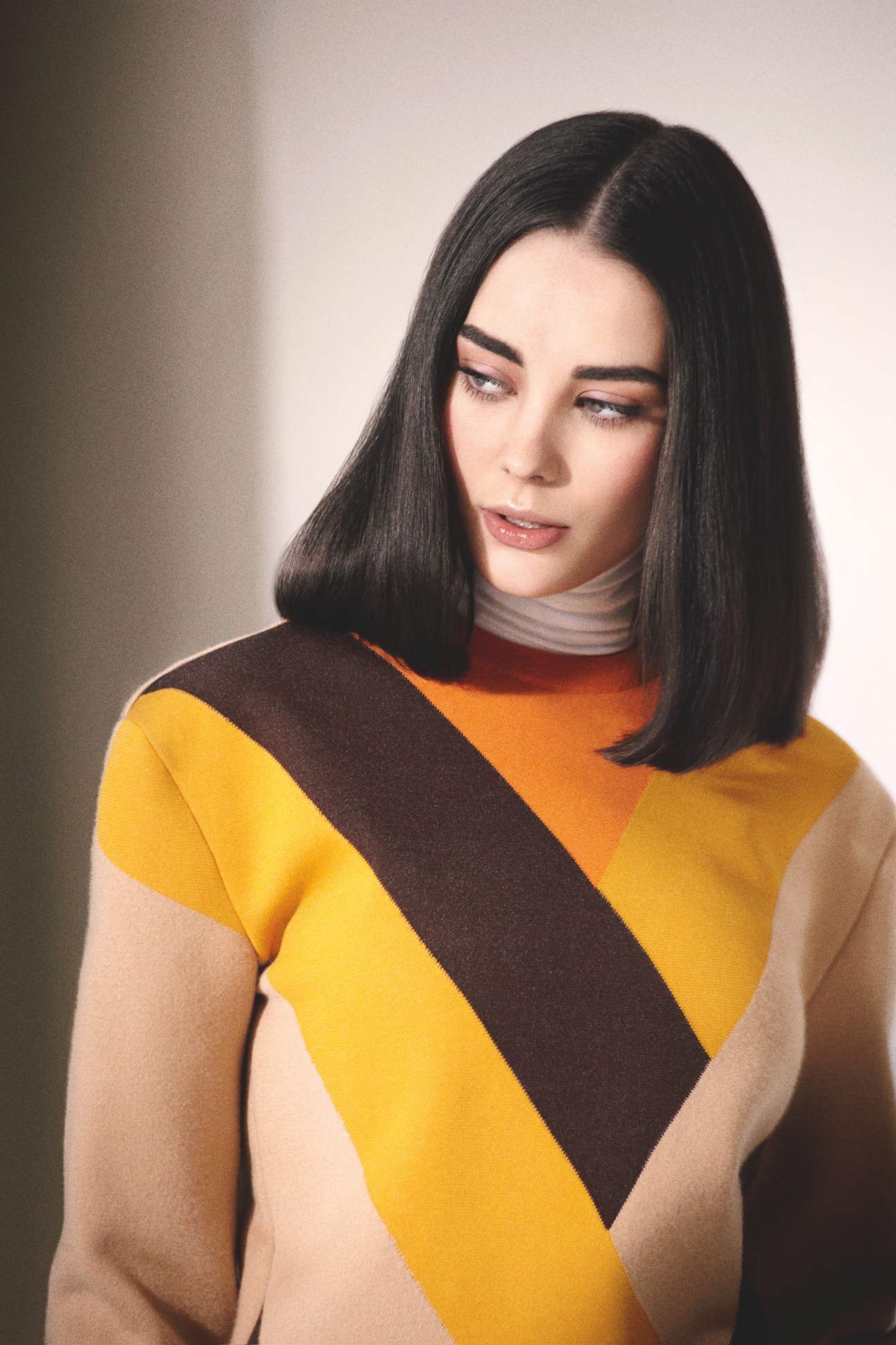 Model wearing a color-block turtleneck and jumper by Céline in yellow, brown and orange tones.