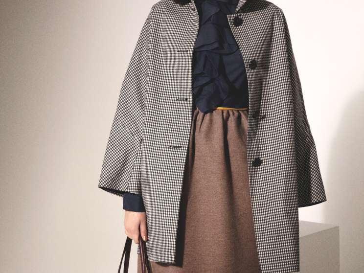 Model wearing a Mackintosh houndstooth coat over a Fendi brown dress with a navy scarf, carrying a Valextra burgundy bag.