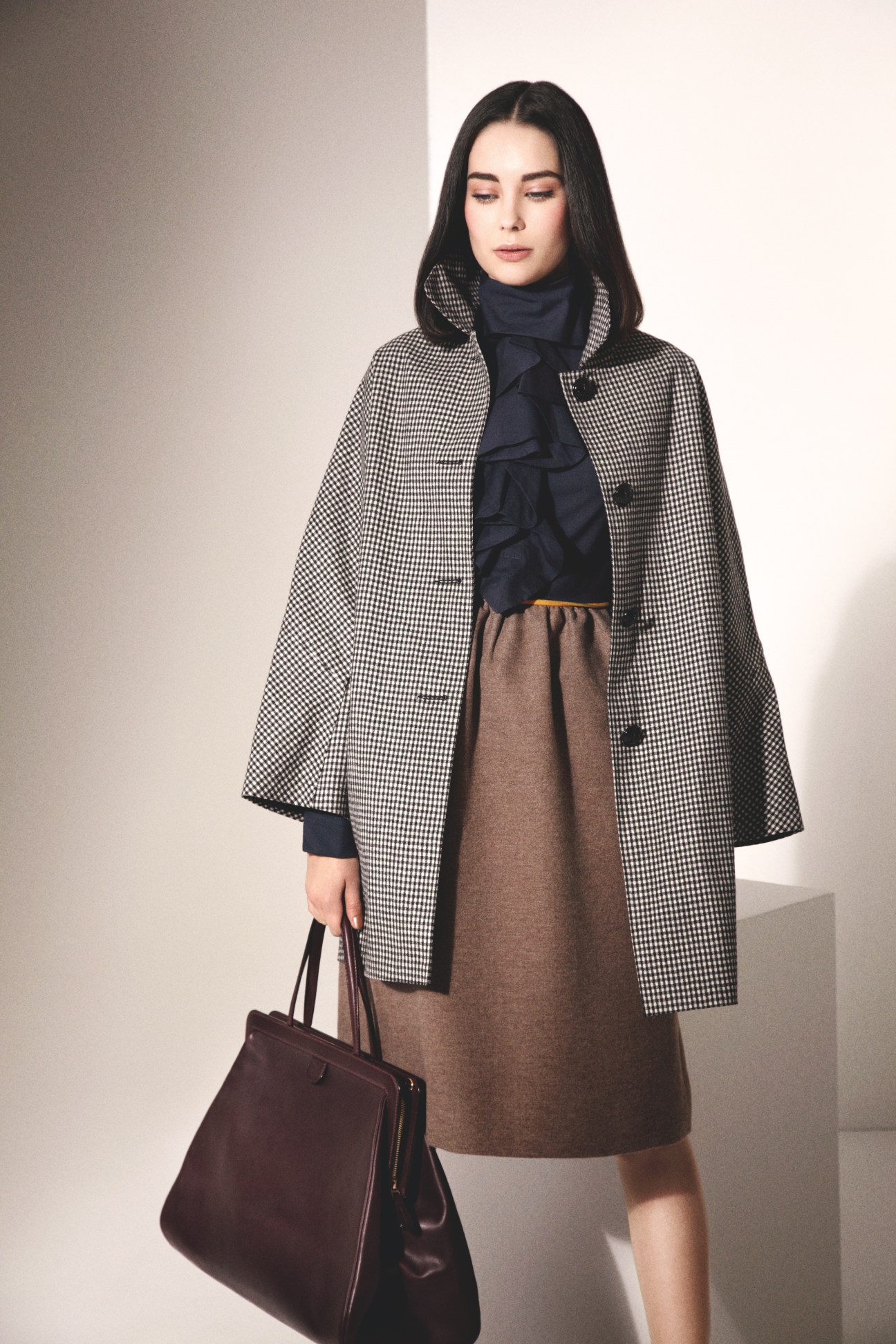 Model wearing a Mackintosh houndstooth coat over a Fendi brown dress with a navy scarf, carrying a Valextra burgundy bag.