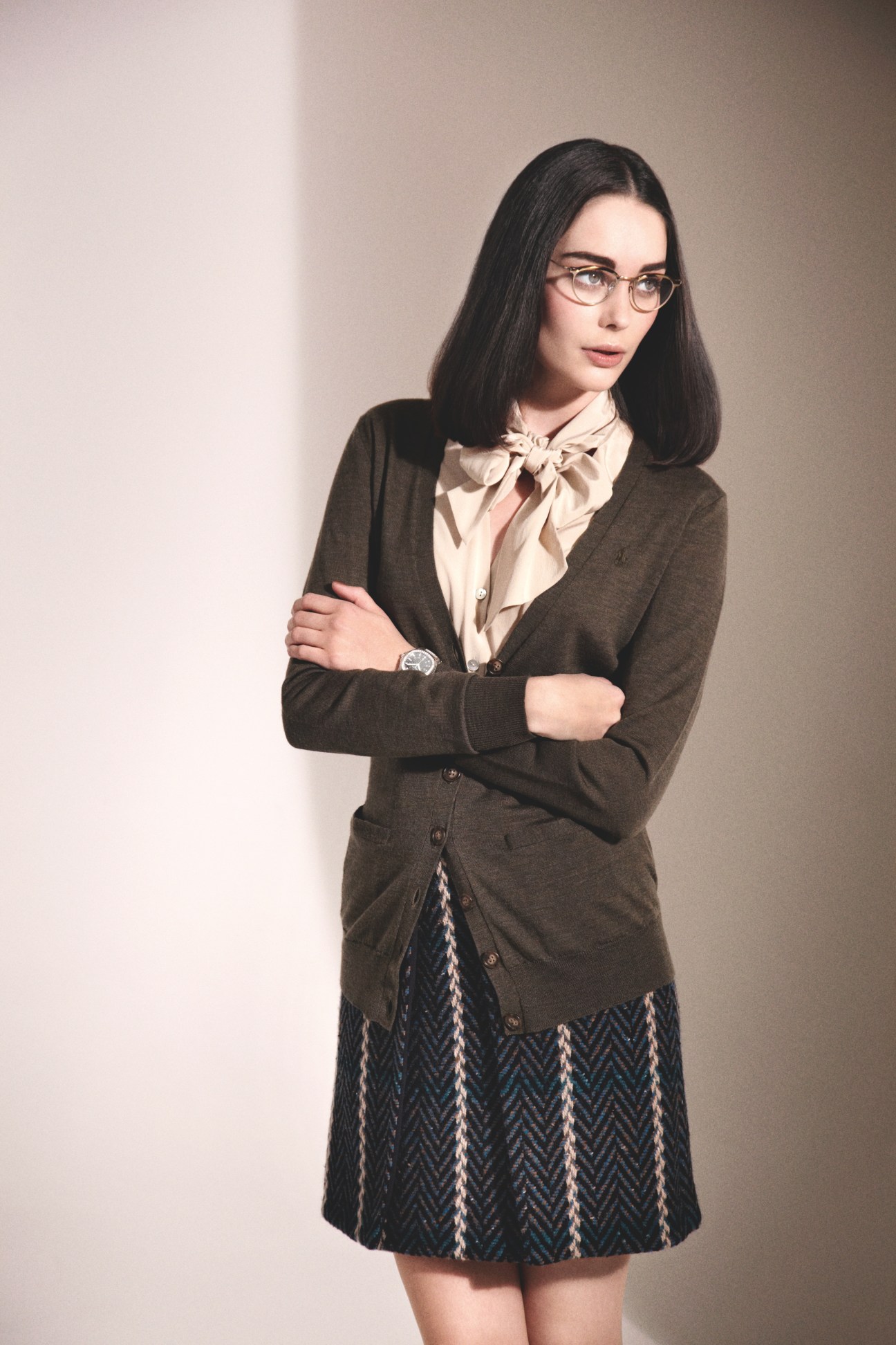 Woman wearing Oliver Peoples glasses, Ralph Lauren cardigan, Beymen shirt, Bally skirt and Patek Philippe watch