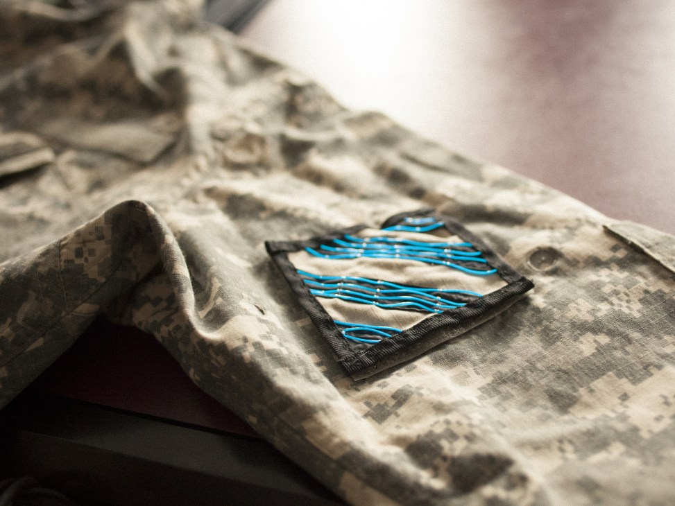 Illuminated LED patch powered by experimental copper wire-woven fabric embedded in textile material.