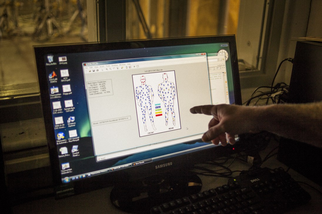 A person points to a computer monitor displaying heat distribution data on a human body diagram with temperature readings in blue and red.