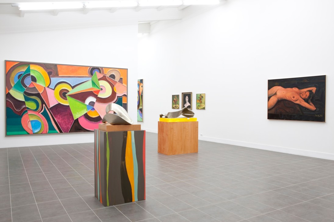 Contemporary art gallery interior with colorful abstract painting, sculptural pedestals, and figurative artworks on white walls.