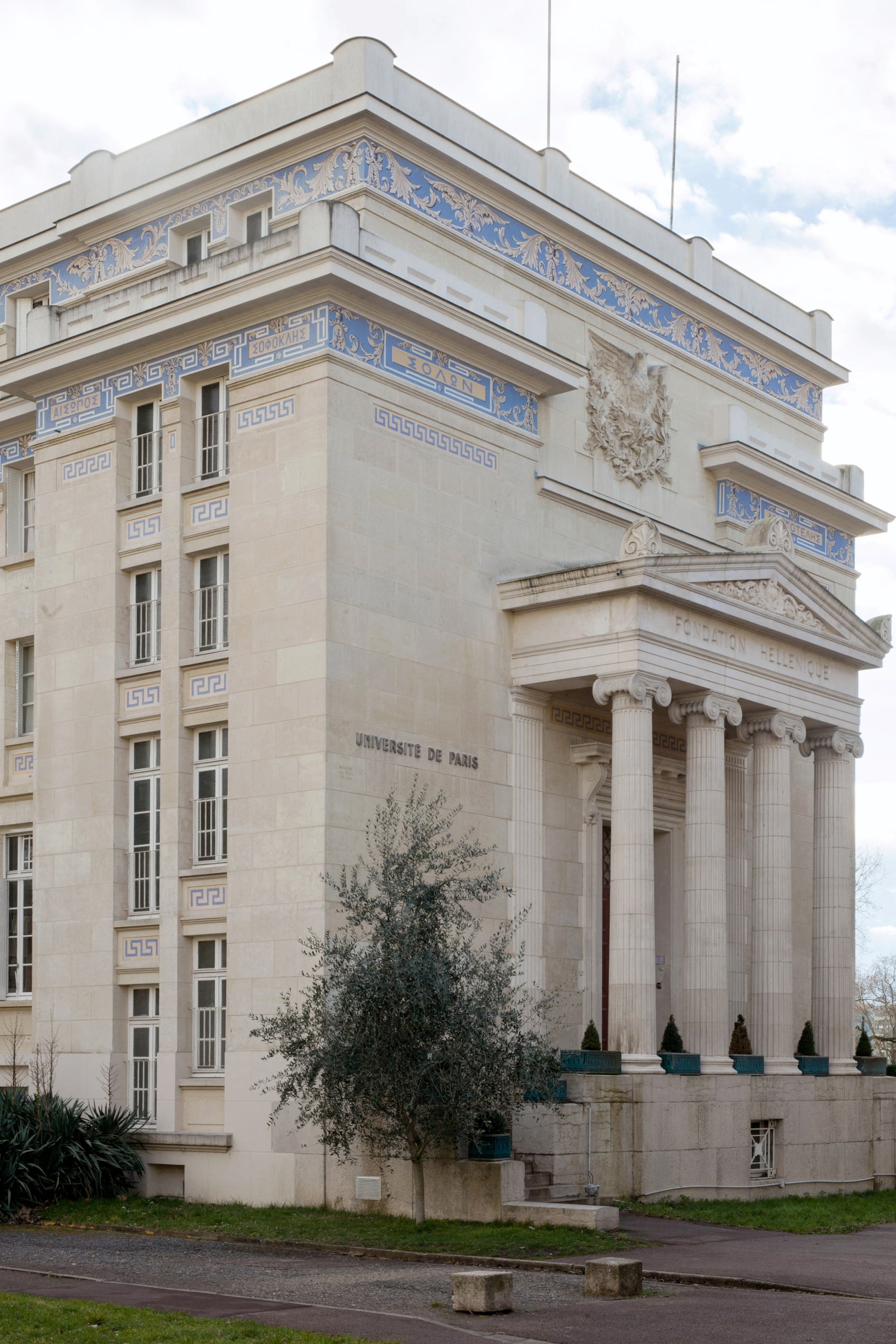 Neoclassical building with cream stone facade, blue and white decorative friezes, and prominent Ionic columns at entrance