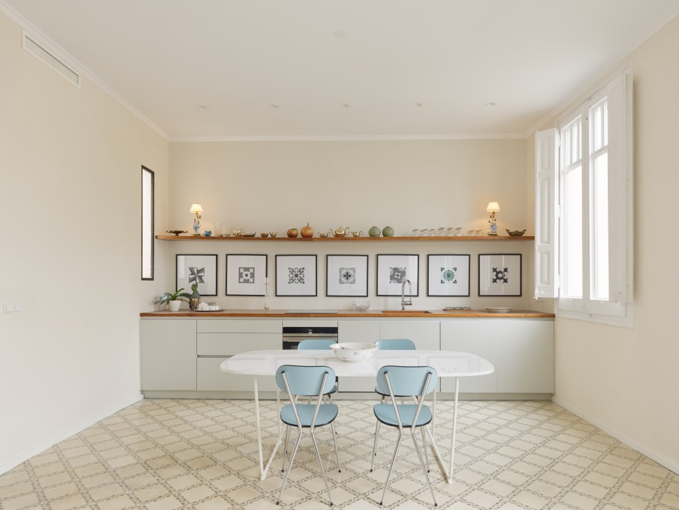 Alexander's refurbished kitchen and dining area with white cabinetry, wooden countertops, patterned floor tiles, and blue chairs.