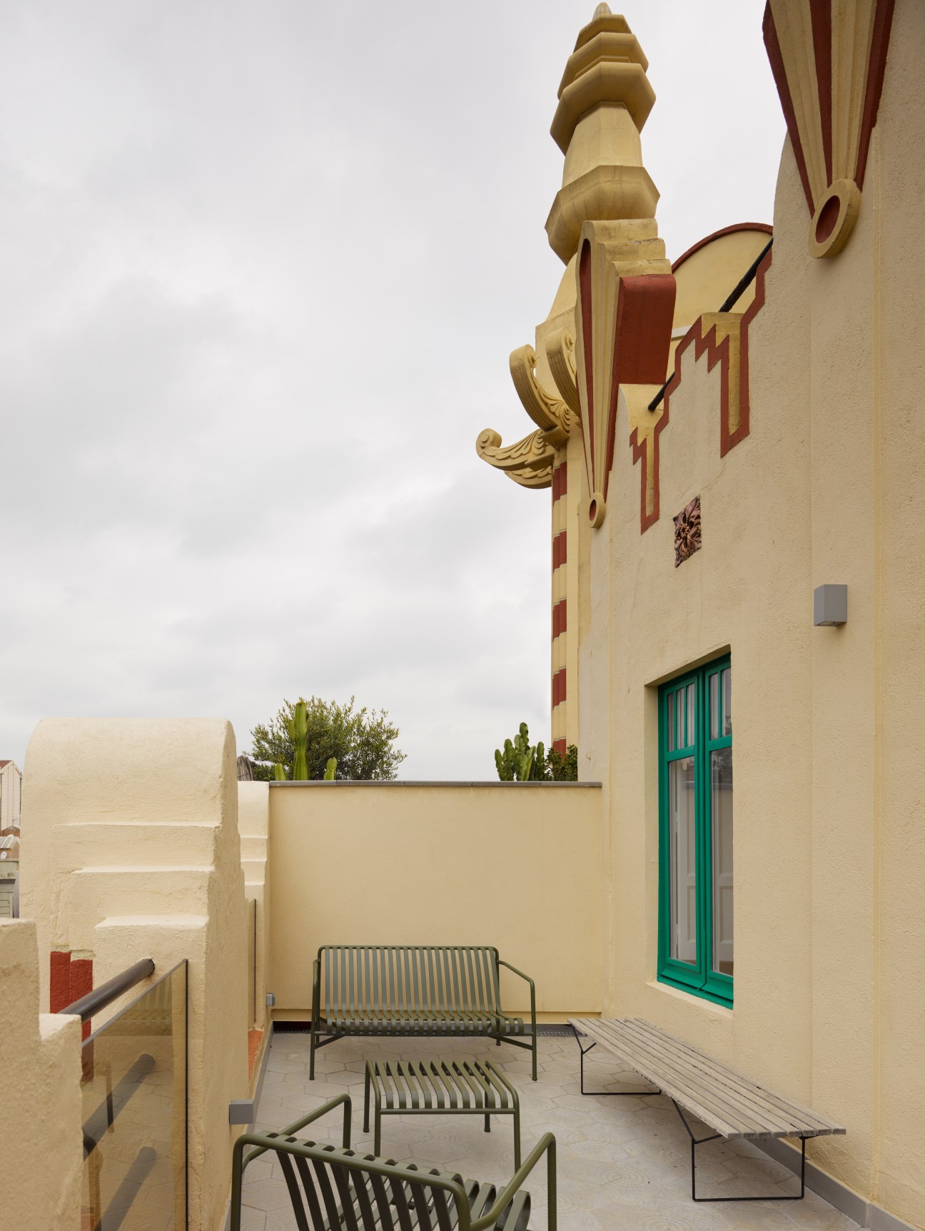 Cream-colored building terrace with modern metal furniture overlooking the street below.