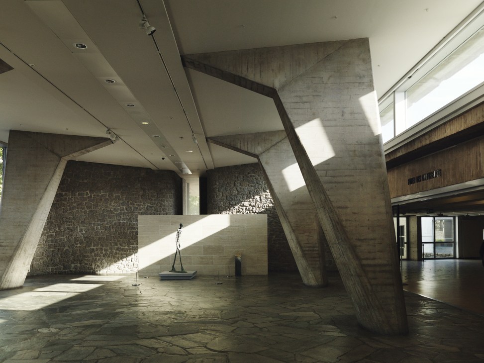 Alberto Giacometti's 'Walking Man' sculpture in Unesco's modernist concrete lobby with angular architectural elements.