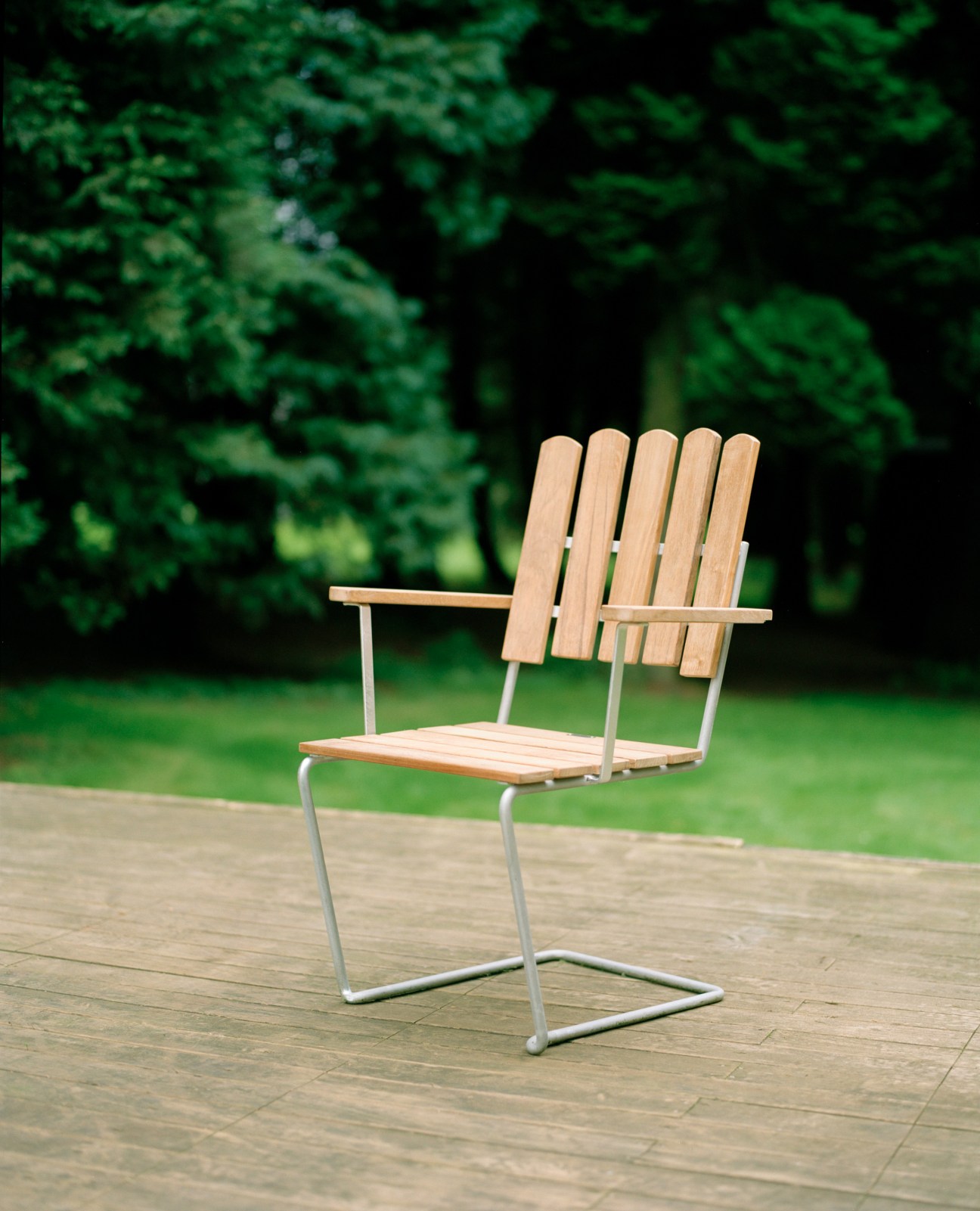 Grythyttan Stålmöbler A2 armchair with natural wood slats and metal frame on outdoor patio.