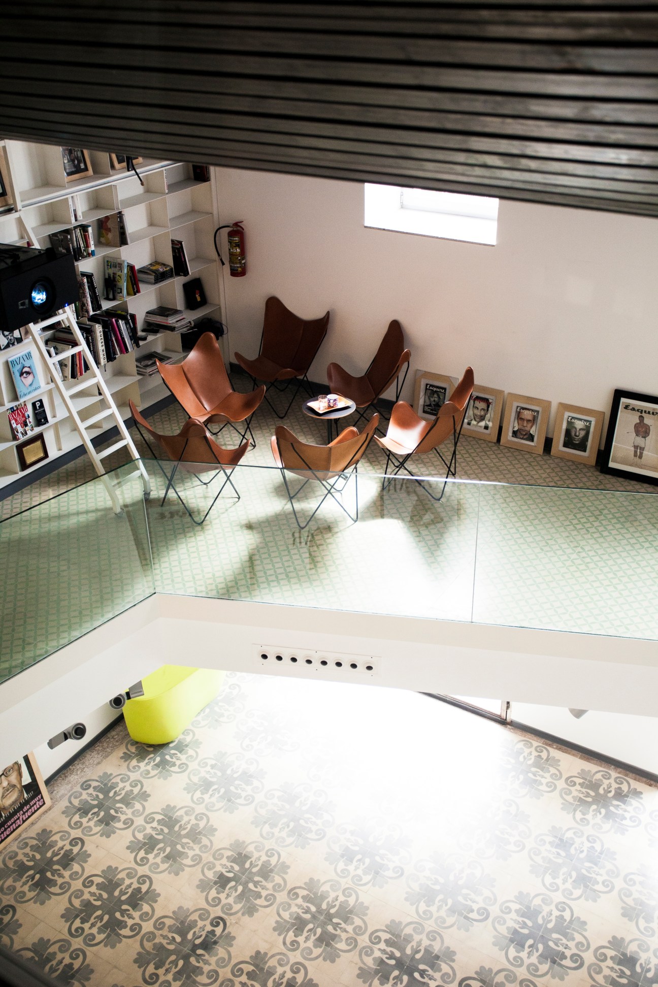 Modern office interior with leather chairs, bookshelves, and framed artwork on walls.
