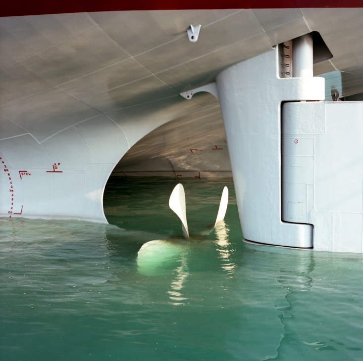 Close-up view of a large ship's stern with twin propellers visible in the water.