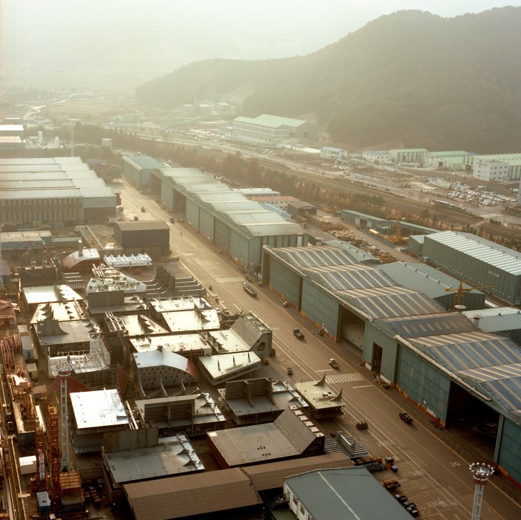 Aerial view of Daewoo Shipbuilding & Marine Engineering yard in Okpo showing massive industrial facilities and construction sites nestled in a valley.
