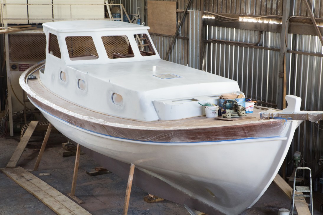A white fishing boat under construction at Guletti boatyard in Bodrum, with wooden hull details and tools nearby.