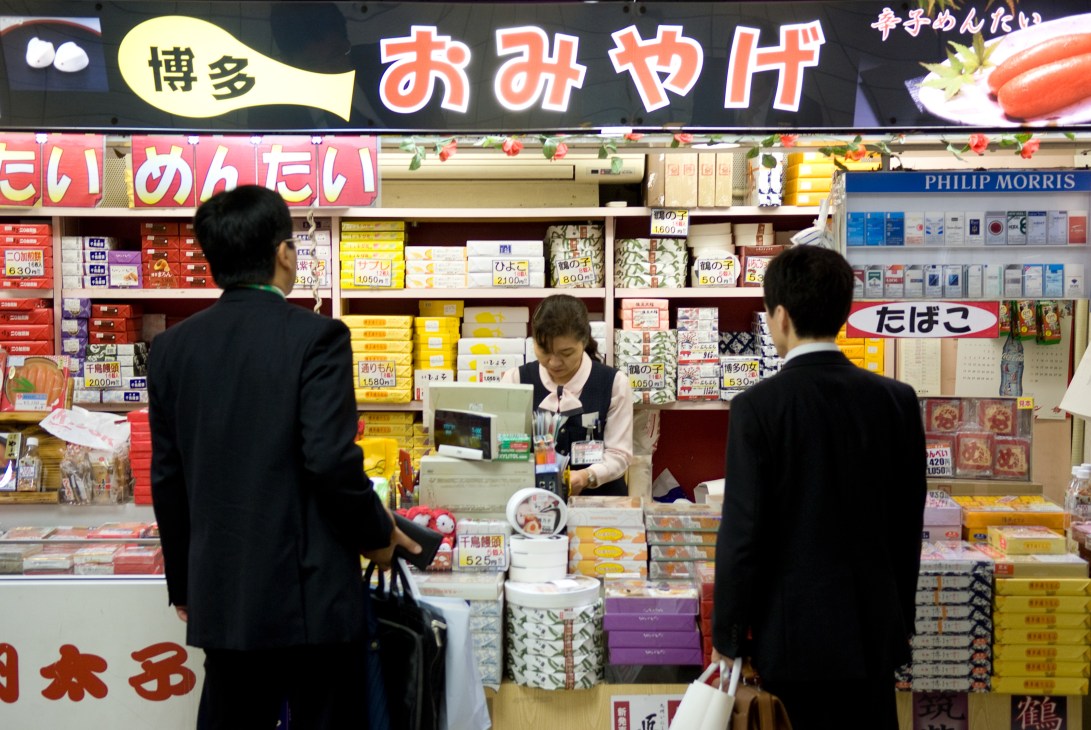 Customers browsing packaged souvenirs at a shop counter in Hakata station