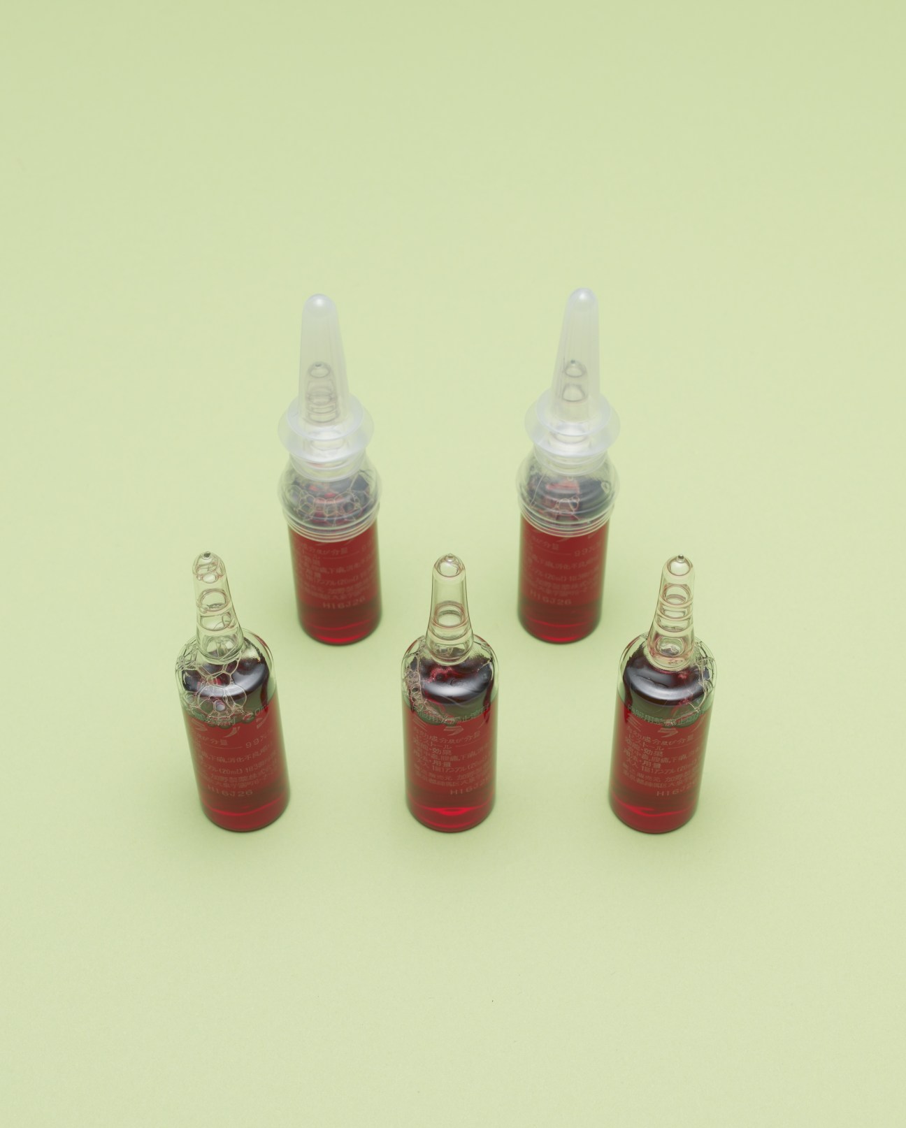 Miranon hangover cure vials with red liquid and white caps arranged on pale yellow background.