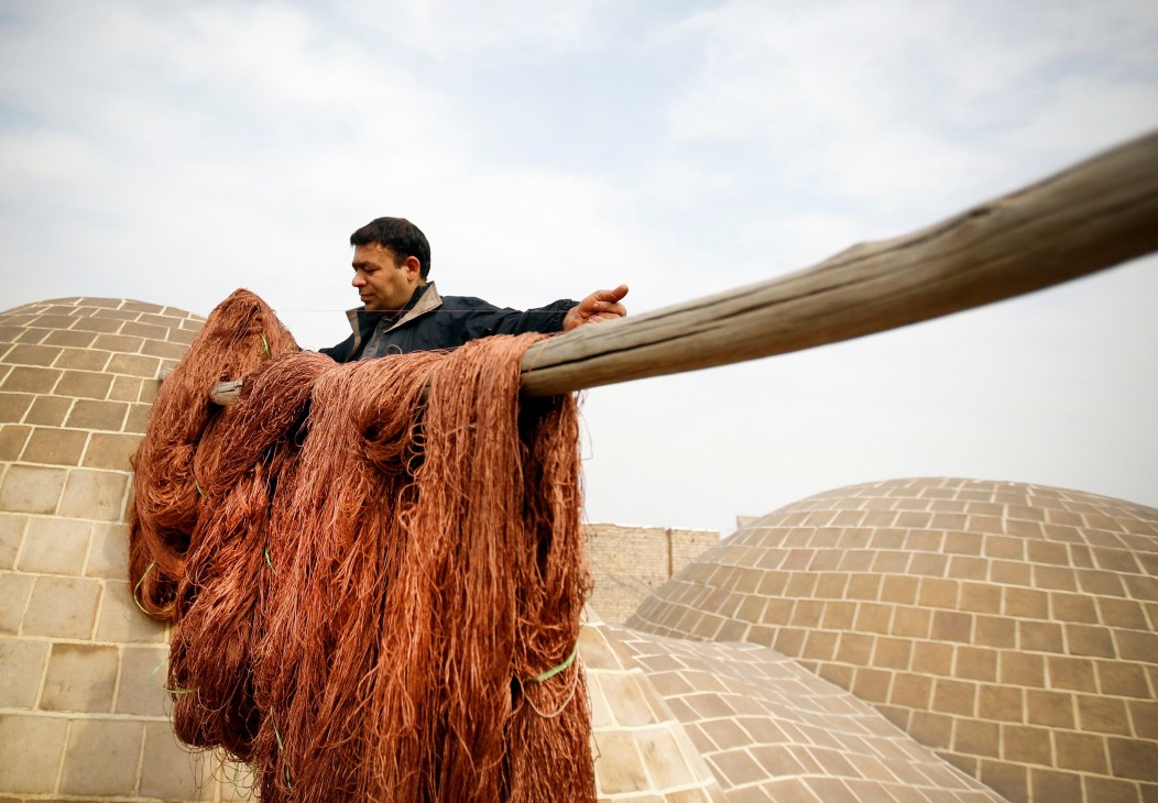 Worker hangs dyed silks to dry at a shop in the holy city of Qom