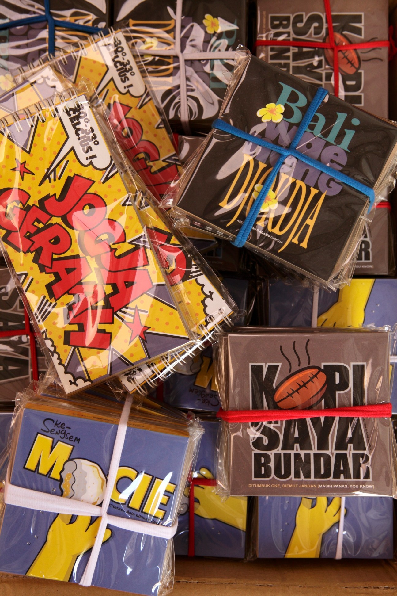 Colorful packaged t-shirts and apparel from Dagadu Djokdja with bold graphic designs and Indonesian text.