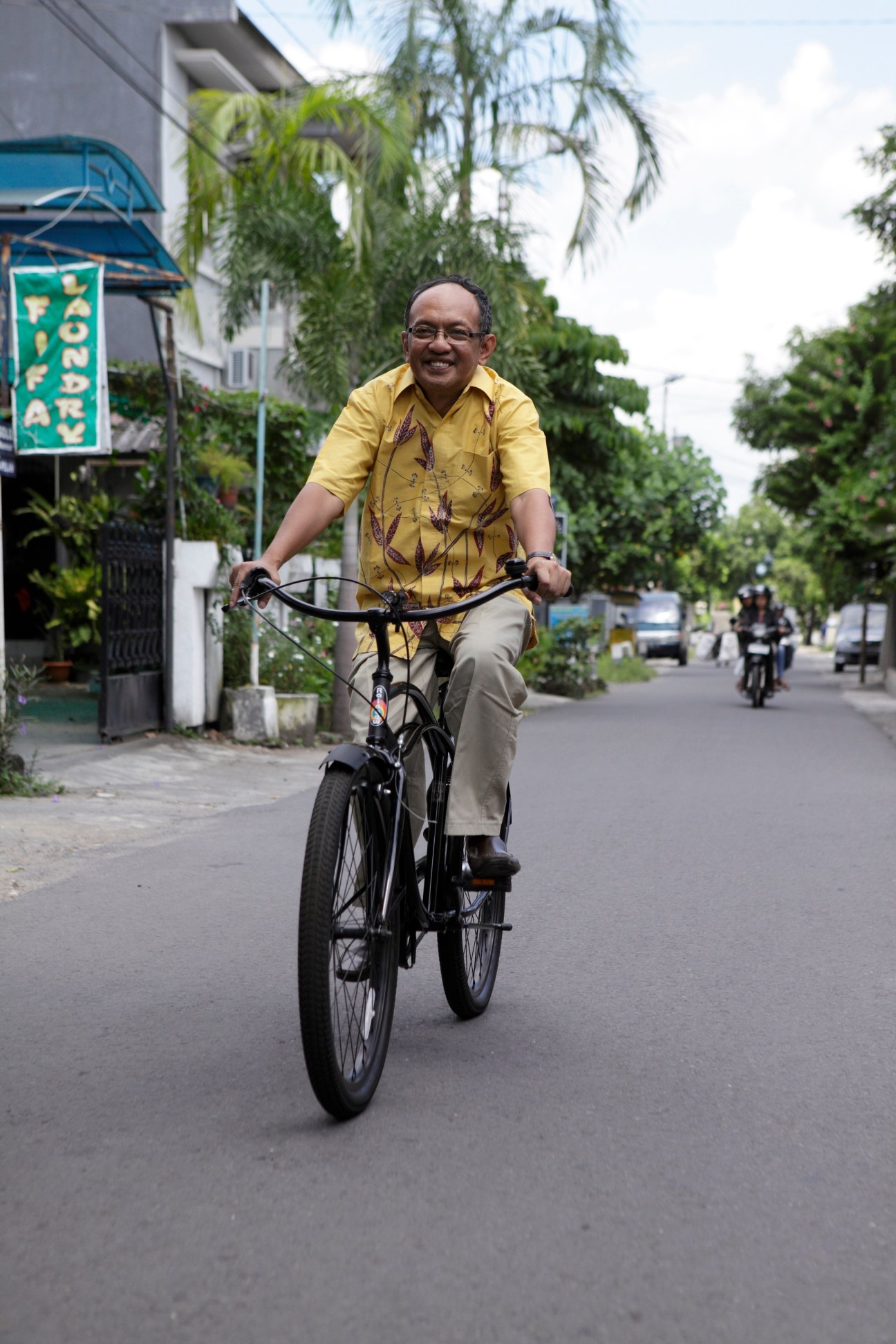 Former mayor Herry Zudianto cycling on a street in Yogyakarta wearing a yellow batik shirt.