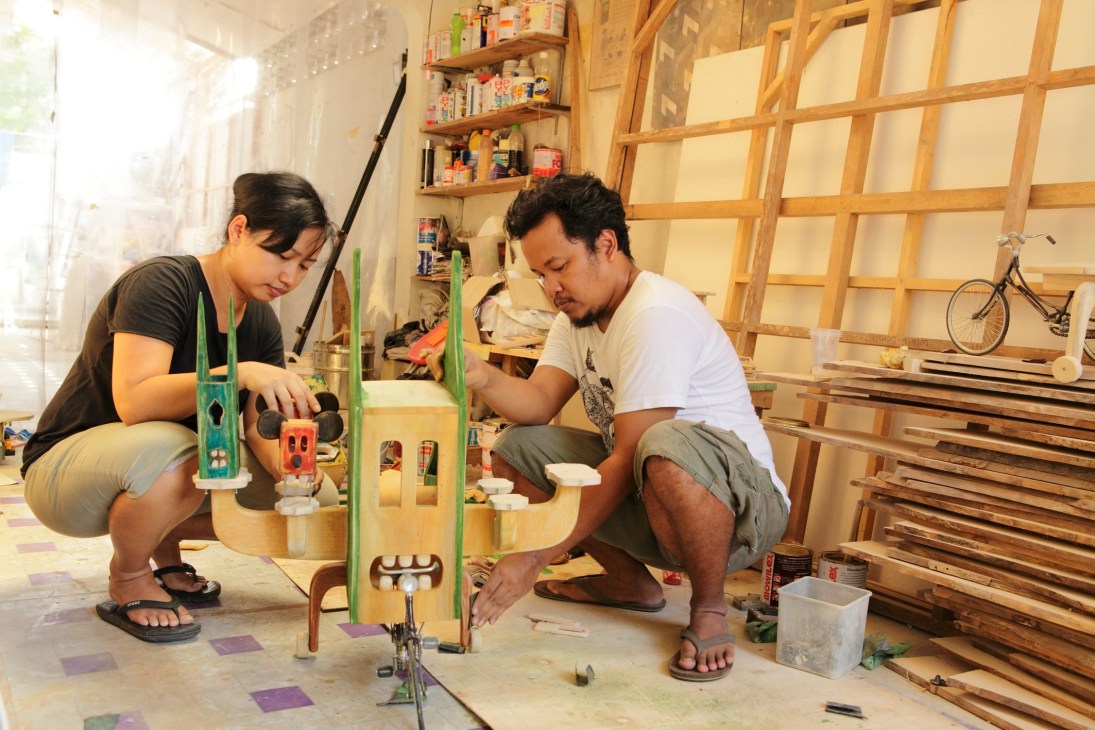 Artists Santi Ariestyowanti and Miko Bawono work on a wooden sculptural piece in their studio.