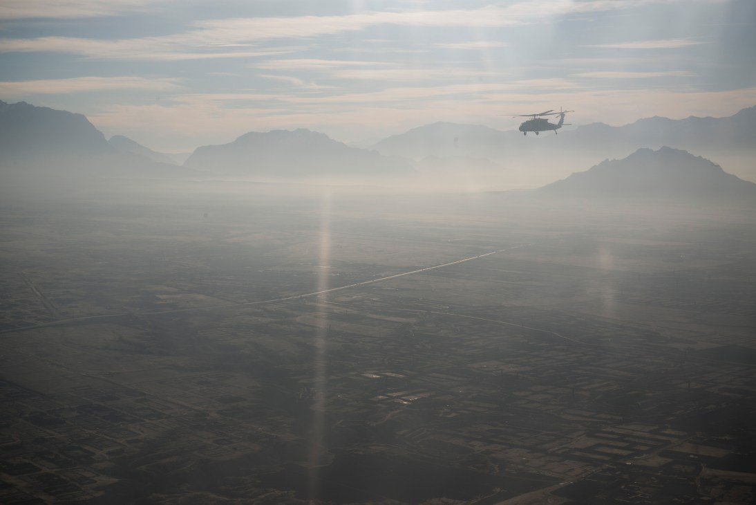 Military helicopter flying over misty Afghan mountains and valley between Kabul and Herat.