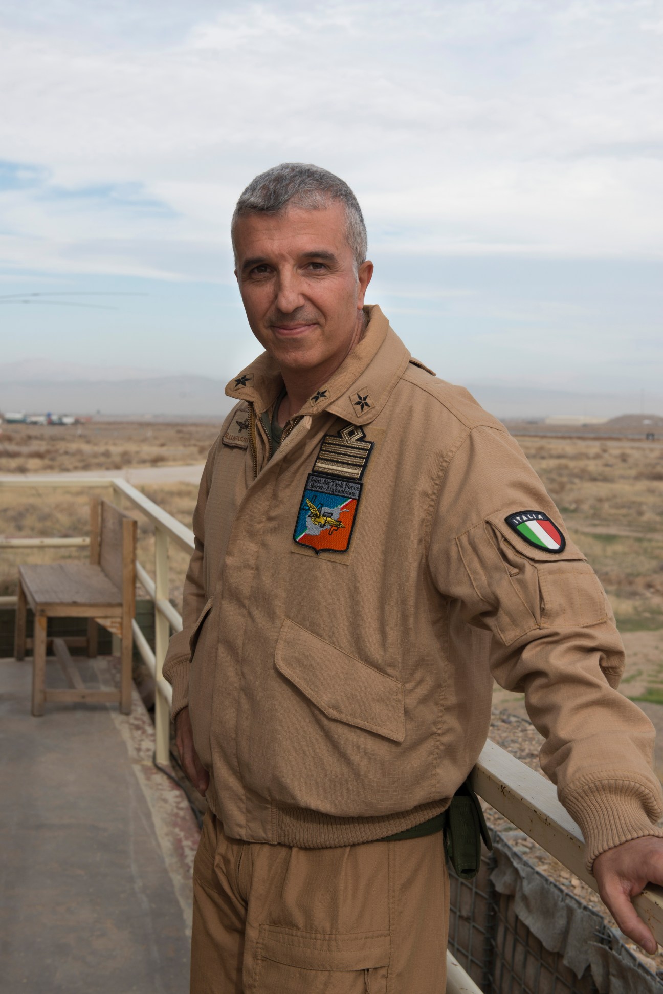 Colonel Raffaele La Montagna, senior air traffic controller, stands in military uniform overlooking an airfield.