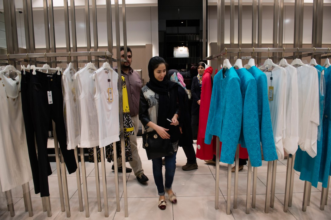Woman in black headscarf browses colorful clothing at Balizzia boutique in Palladium mall.