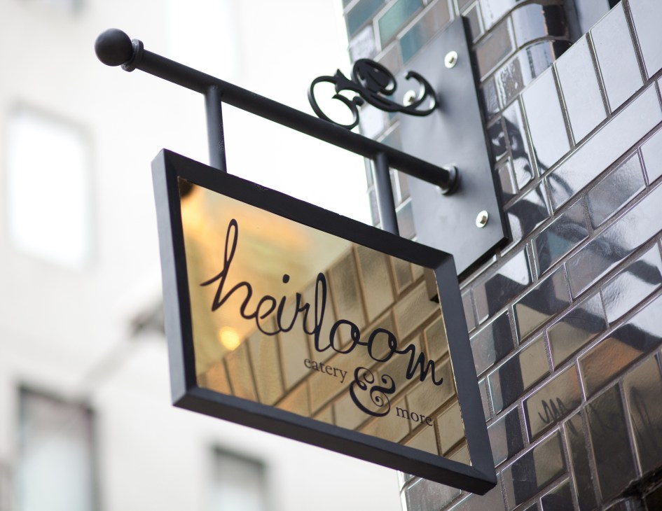 Heirloom restaurant storefront sign with decorative black metal bracket and ornamental details.