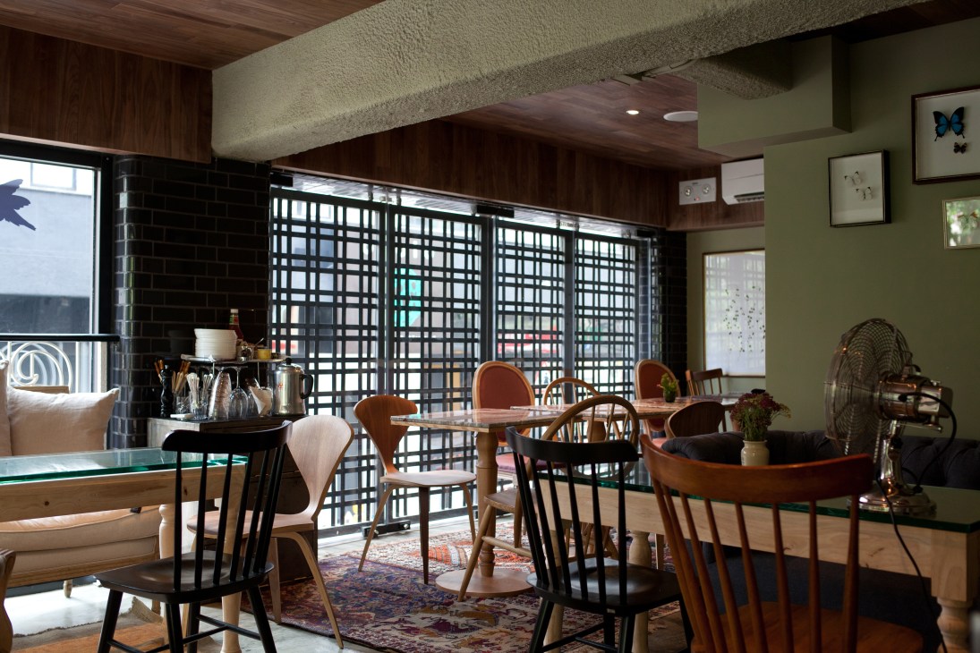 Interior of Heirloom restaurant with mid-century modern furniture, green walls, and latticed partition screens.