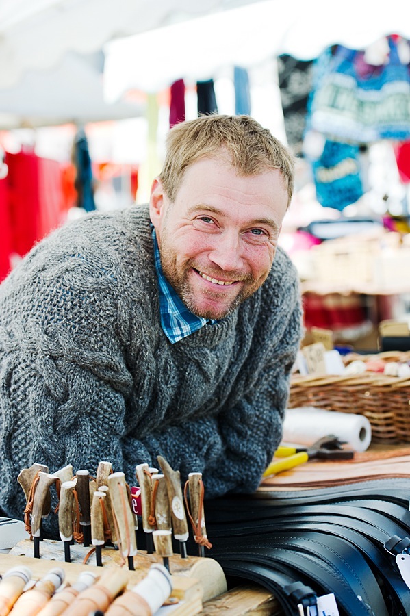 Man smiling at camera with wooden craft items displayed on work table