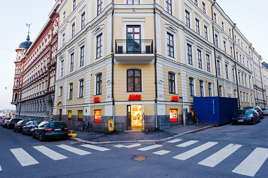 Helsinki street corner with period architecture, storefronts, and pedestrian crossings.