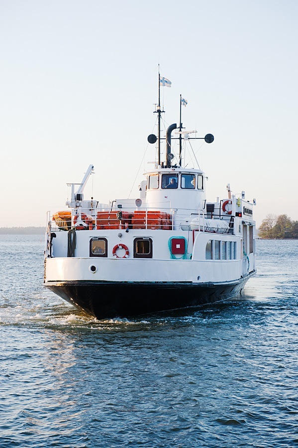 White and red ferry boat with Finnish flags on the water.