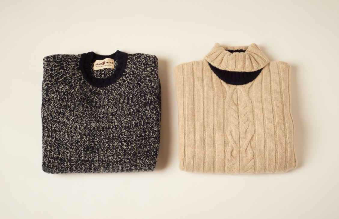 Two knitted wool jumpers from Alan Paine's English Explorer collection, one charcoal and one cream-colored with cable knit details.