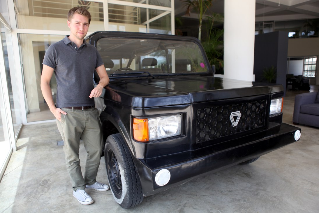 Joel Jackson standing beside the Mobius, a black utility vehicle designed for African roads.