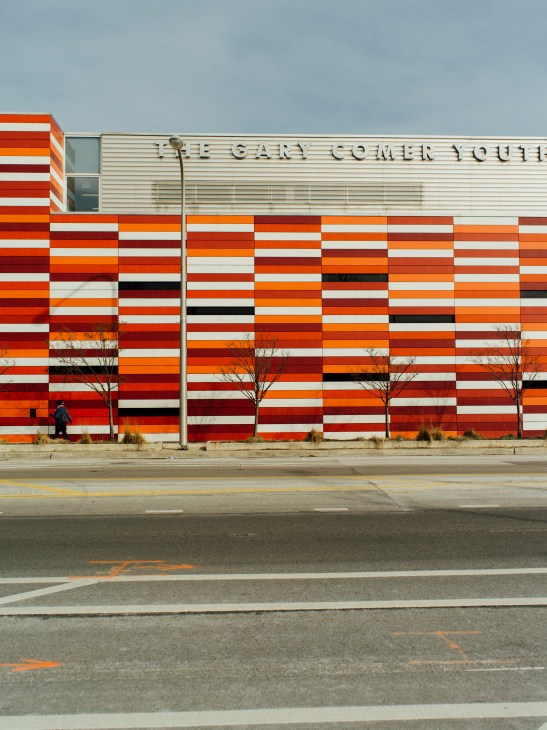 Gary Comer Youth Center with bold red, orange and white horizontal striped facade and street-level windows.