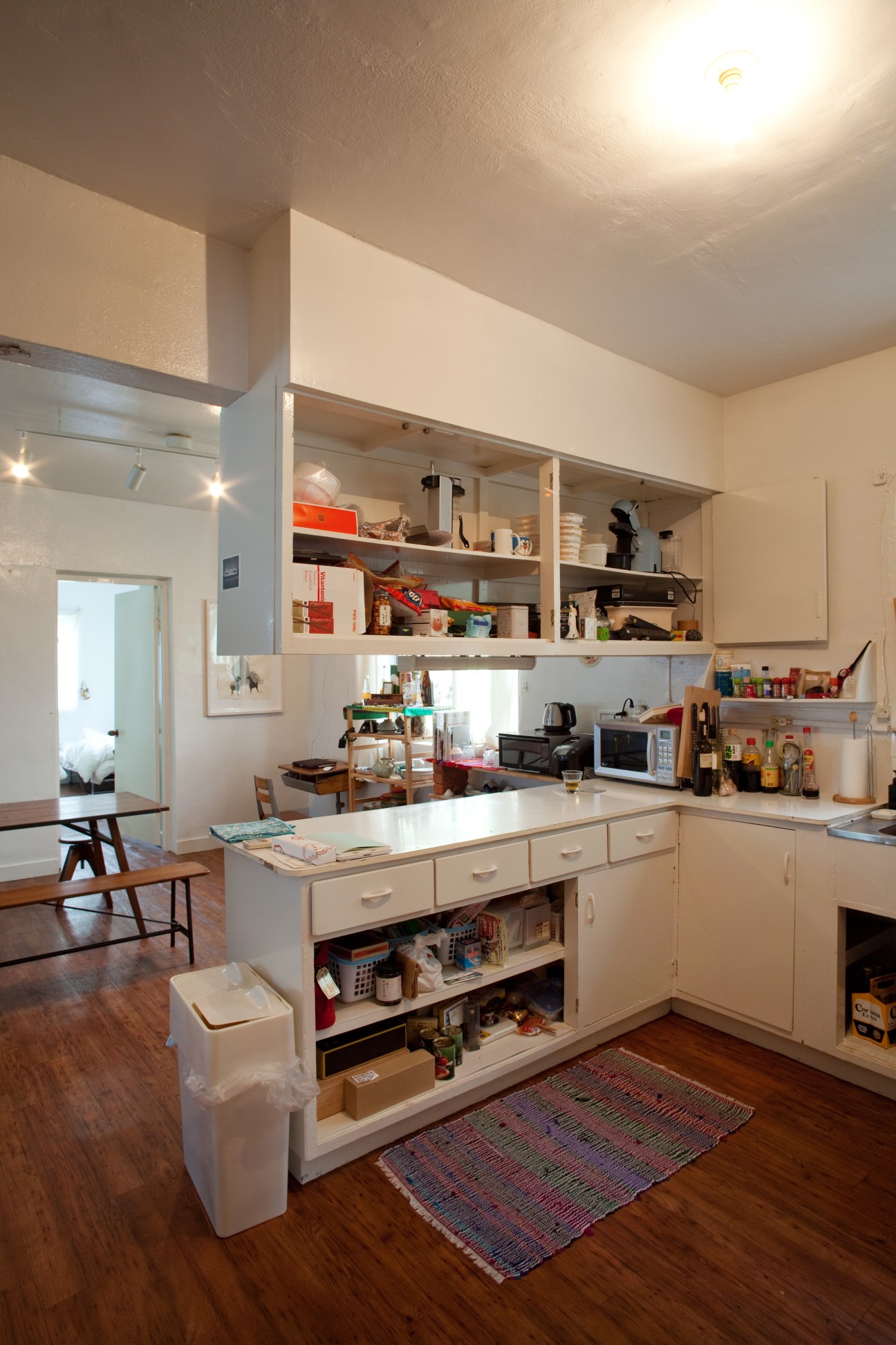 A modern kitchen with white cabinetry, open shelving, and a central island in a spacious post-war military residence.
