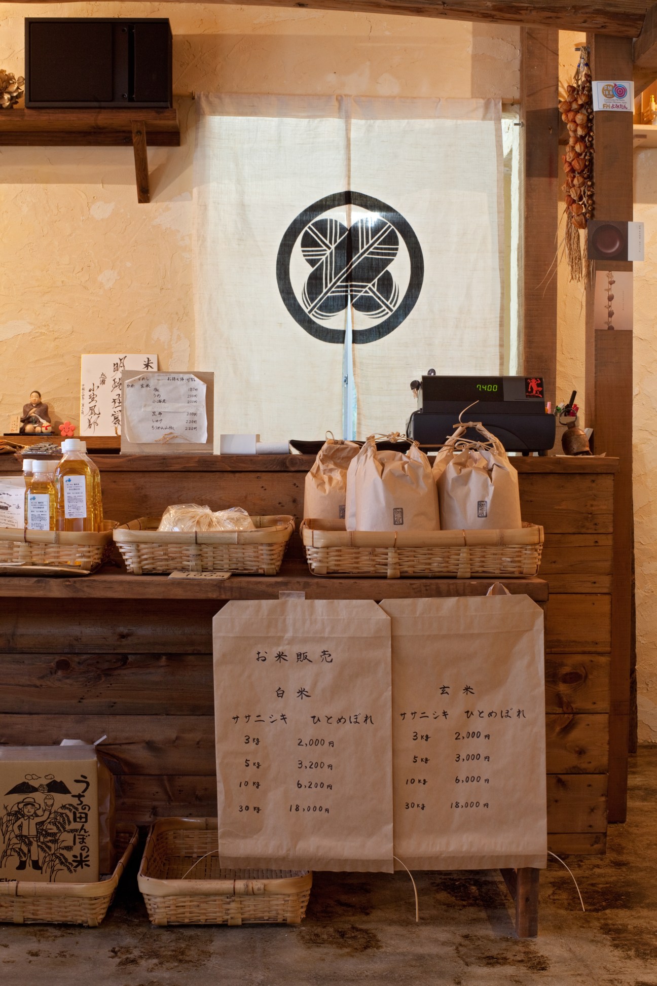 Rice display counter at Komeya Matsukura with baskets and paper bags showing prices.