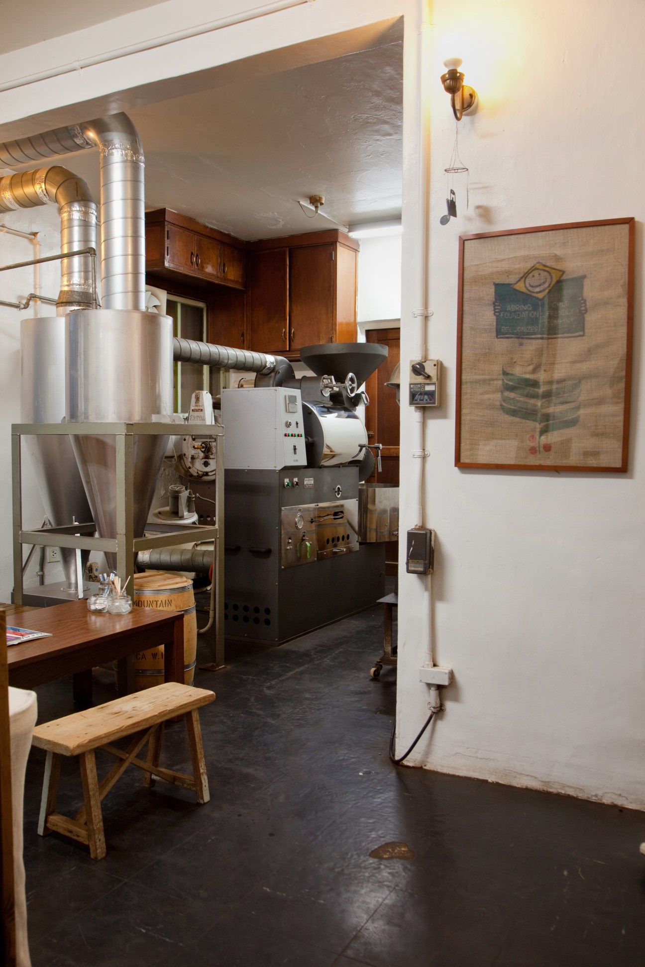 Industrial coffee roaster with metal pipes and machinery in a converted military house space.