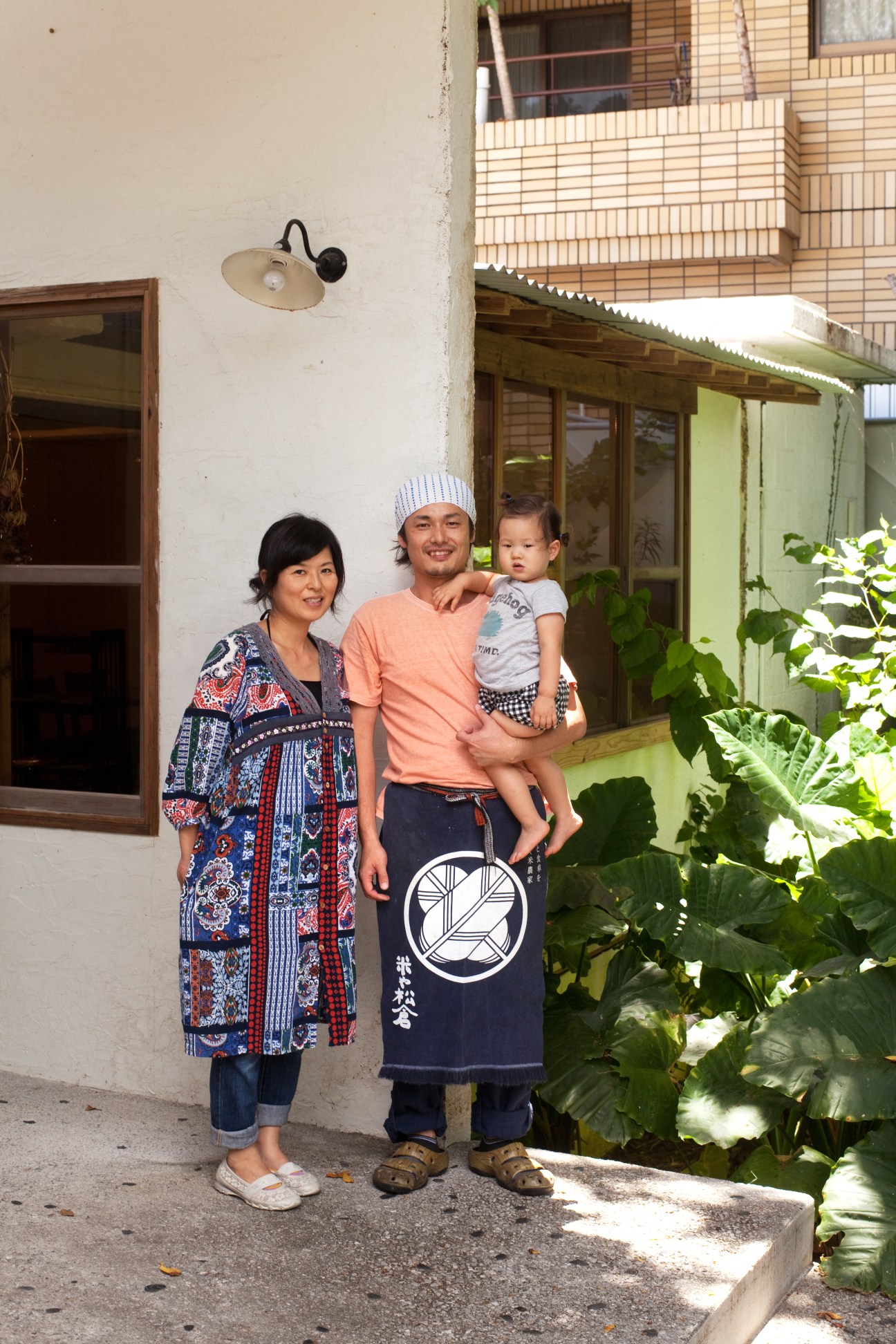 Hayato Asano stands with his wife Shiho and daughter Hinata outside their concrete military house in Okinawa.