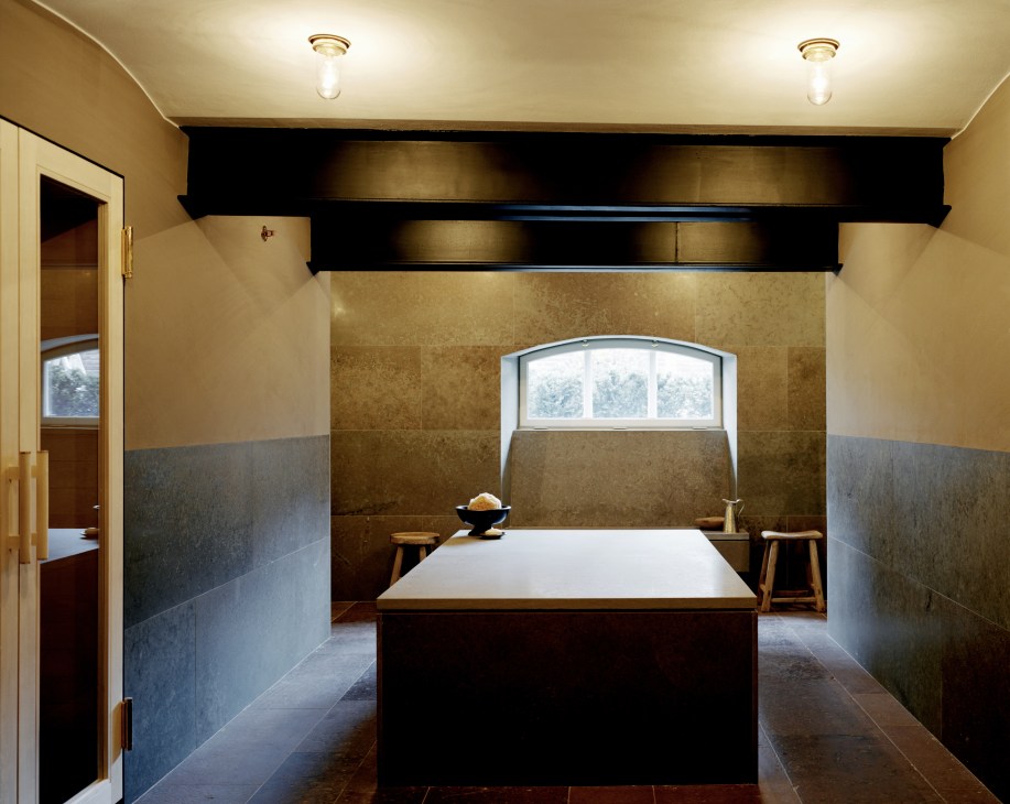 Minimalist spa room with a rectangular hot stone table and sauna features marble and slate finishes.