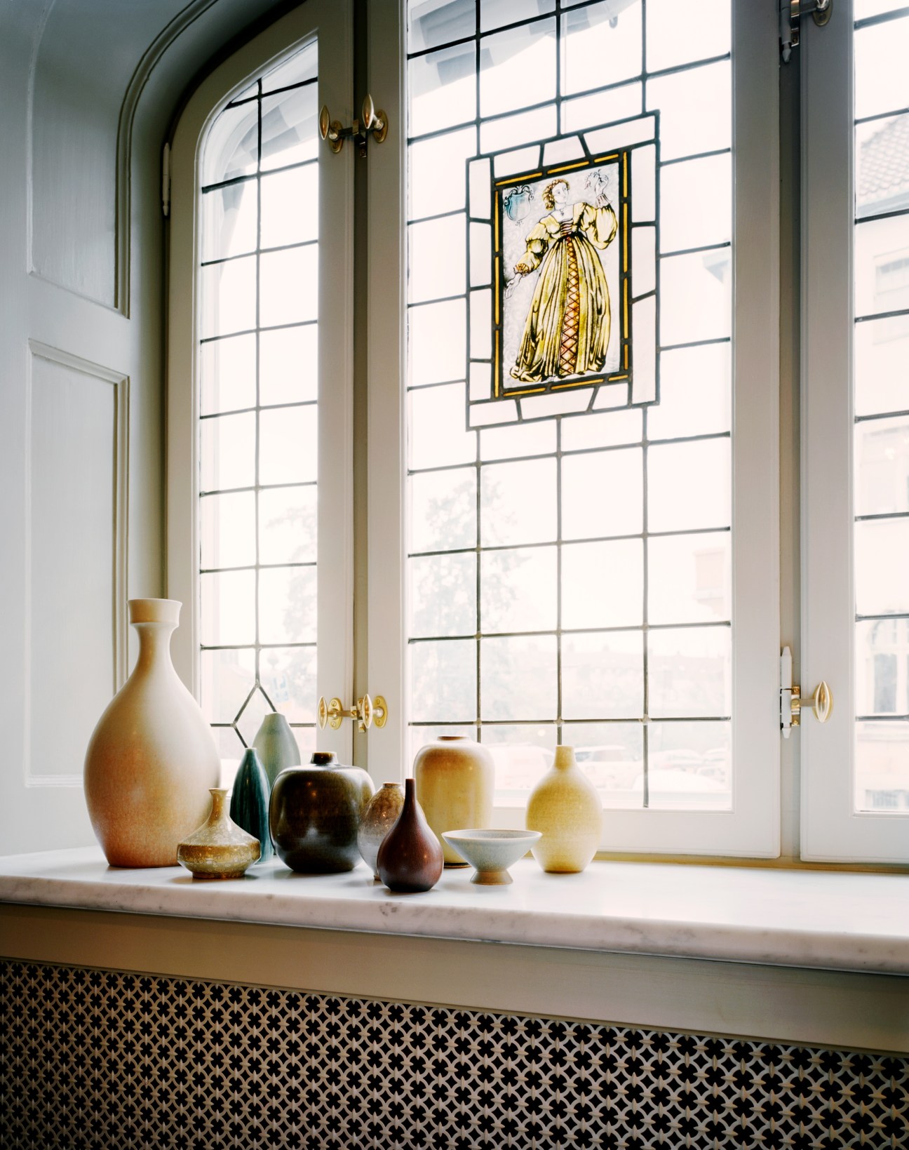 Windowsill displaying Jeanette Mix's art and object collection with ceramic vessels and a framed artwork.