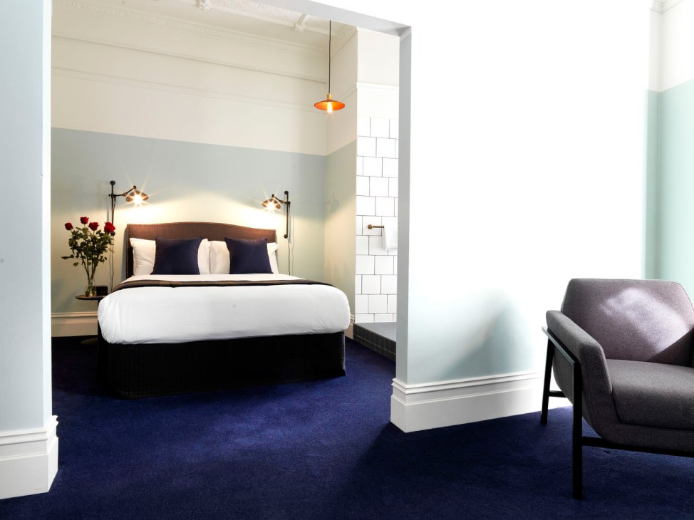 Hotel Harry suite in Sydney with bed, chair, and modern lighting design on blue carpet