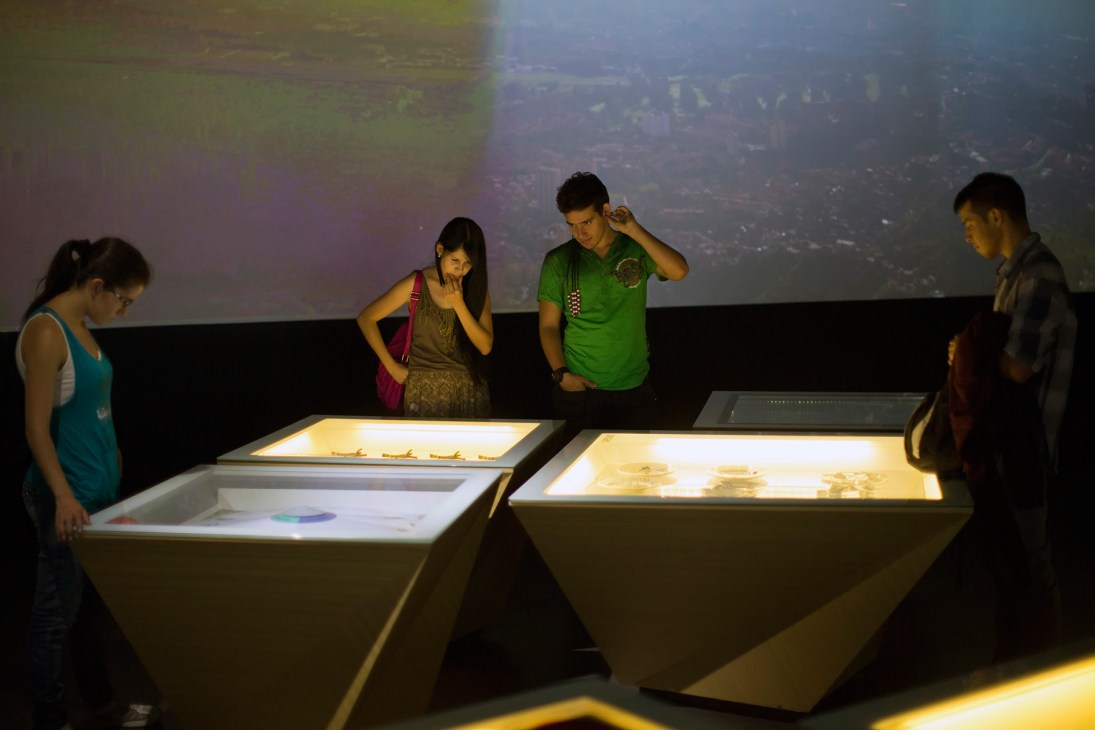 Visitors viewing illuminated exhibits inside the House of Memory museum in Medellín.
