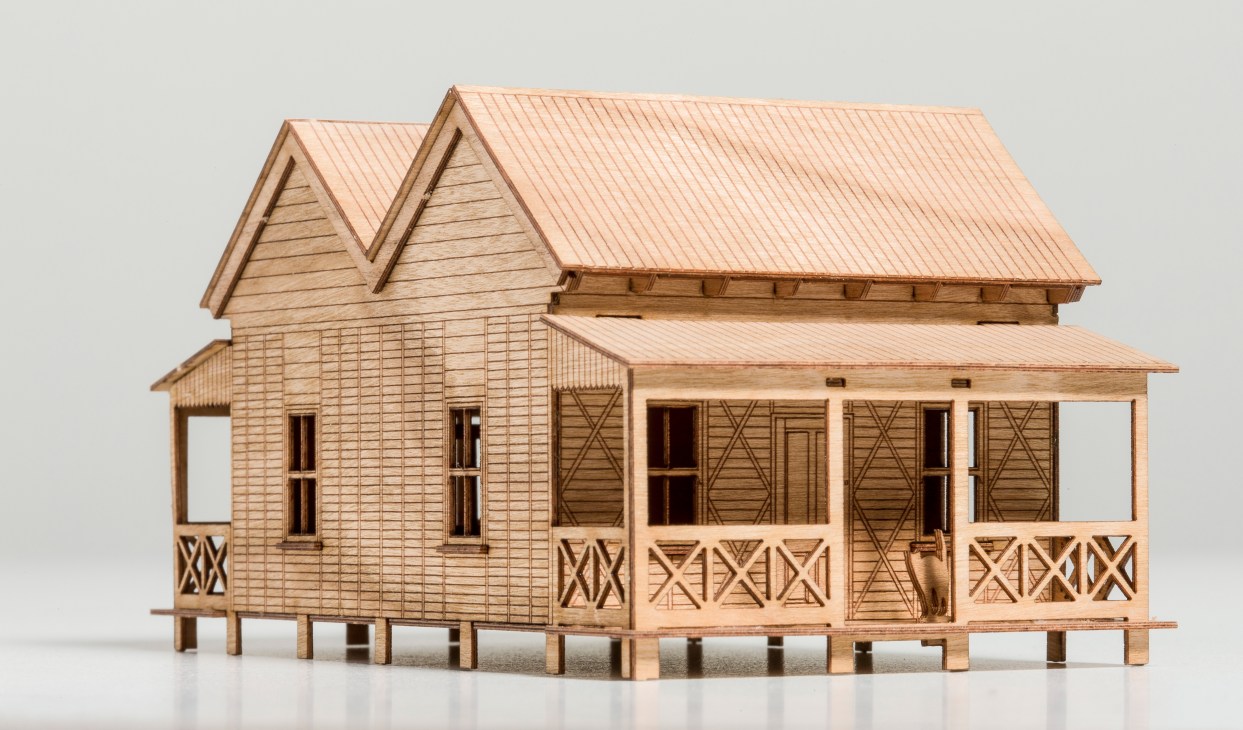 Wooden miniature model of a Queensland vernacular house with elevated timber construction, weatherboard cladding and metal roof.