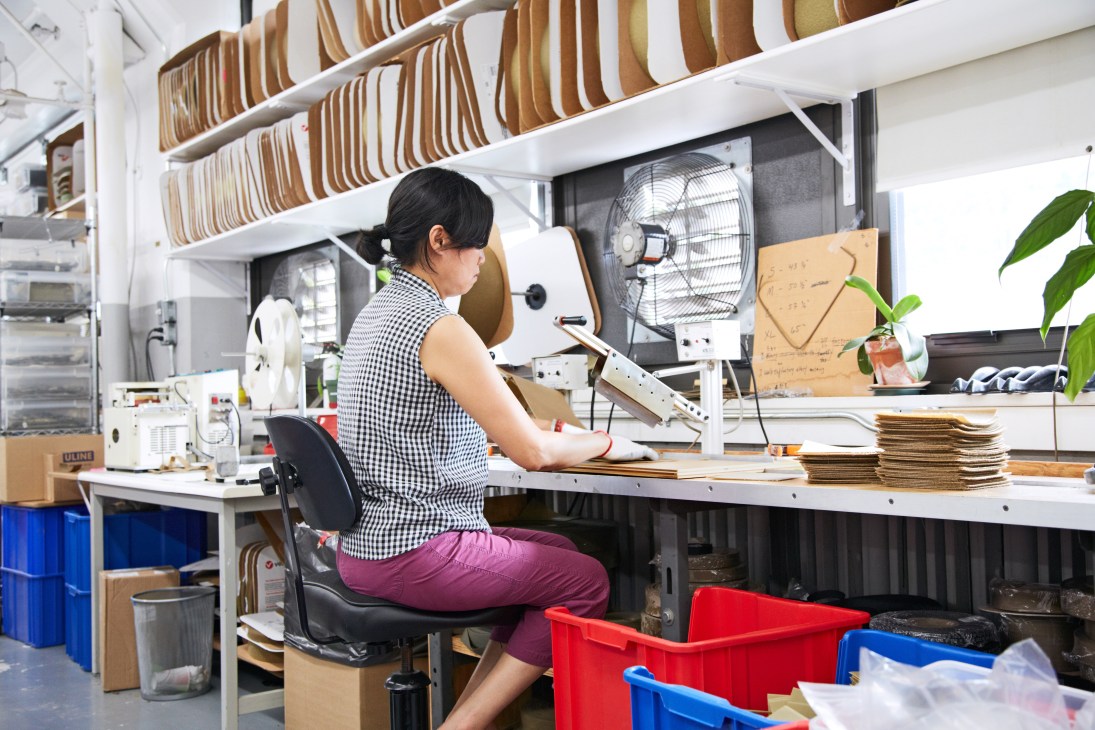 Worker sewing MultiCam fabric at a desk in Crye Precision's Brooklyn facility.