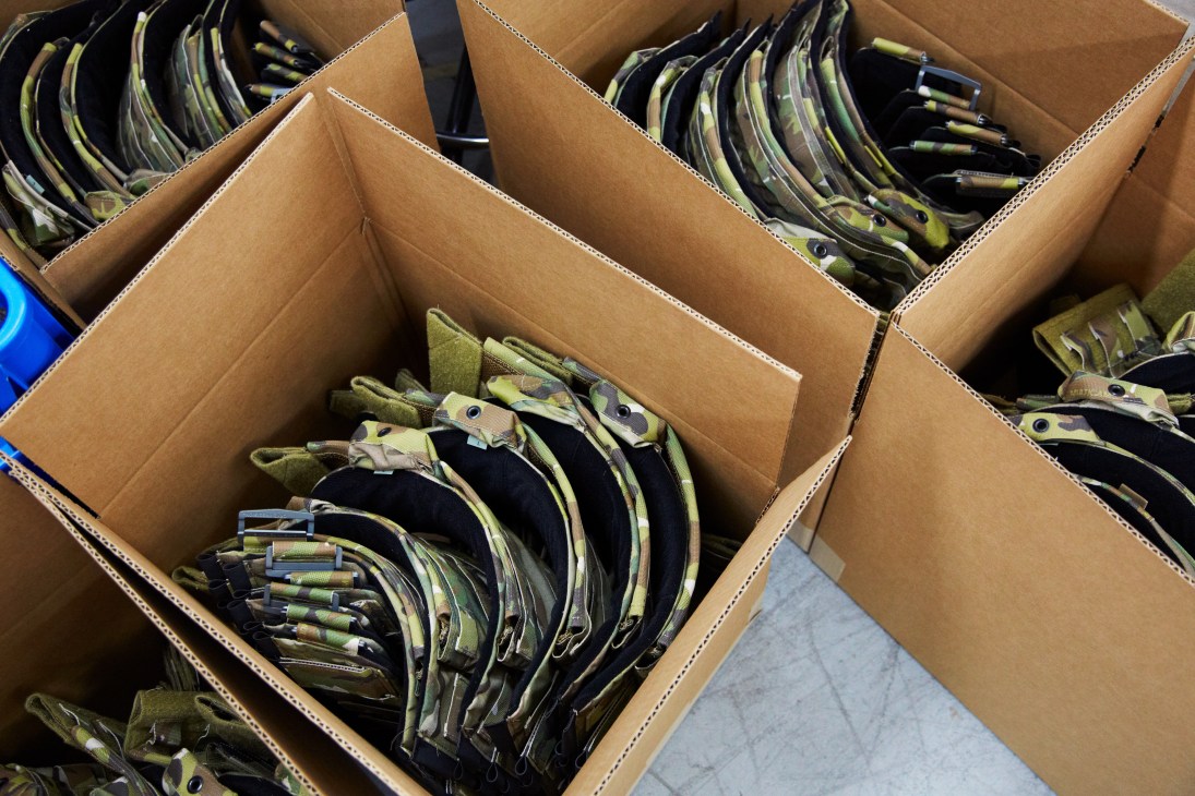 Cardboard boxes filled with stacked MultiCam pouches and straps ready for shipment.