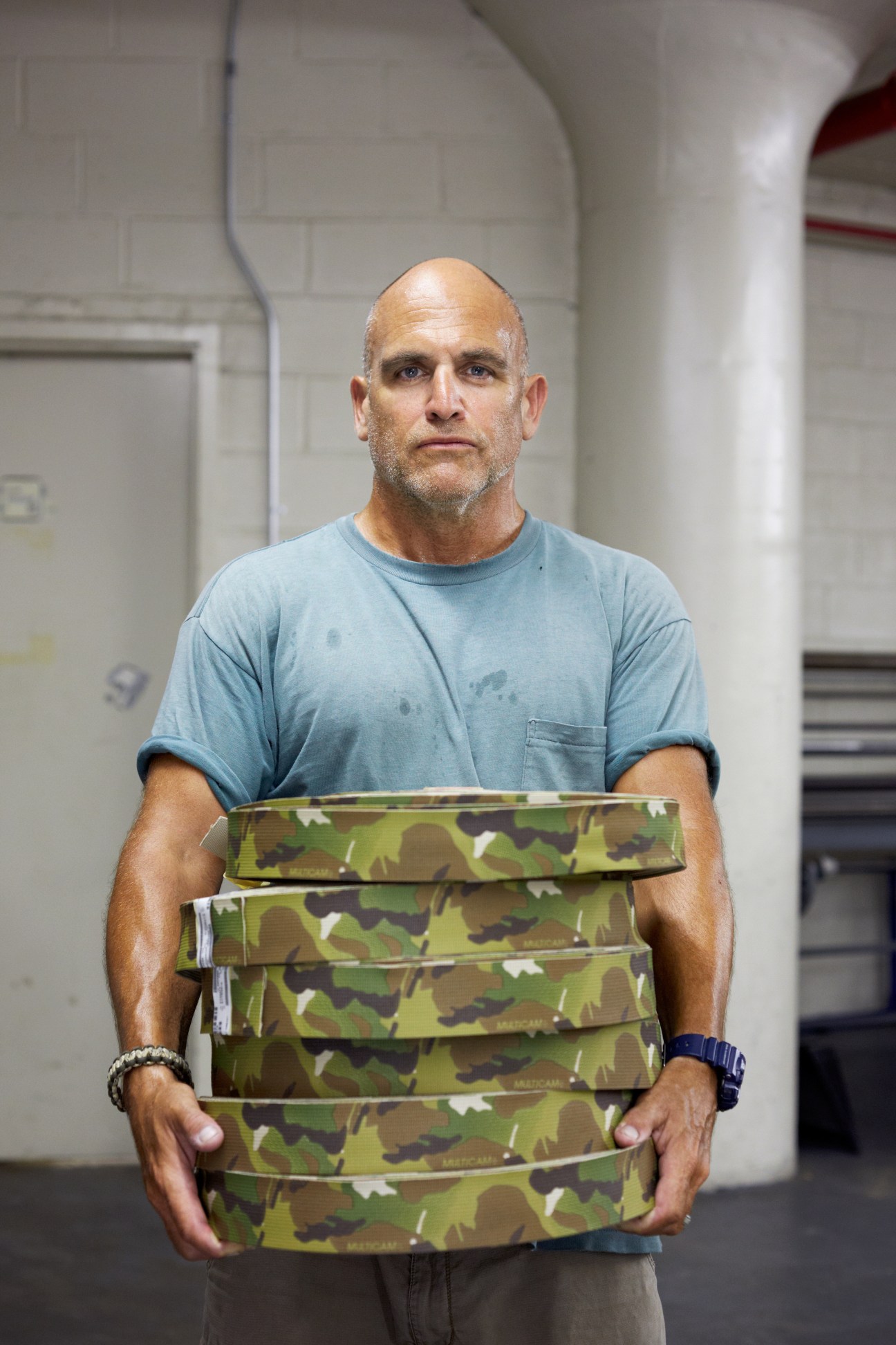 John Sharian, quality manager at Crye Precision, holding stacked rolls of MultiCam webbing in the Brooklyn factory.