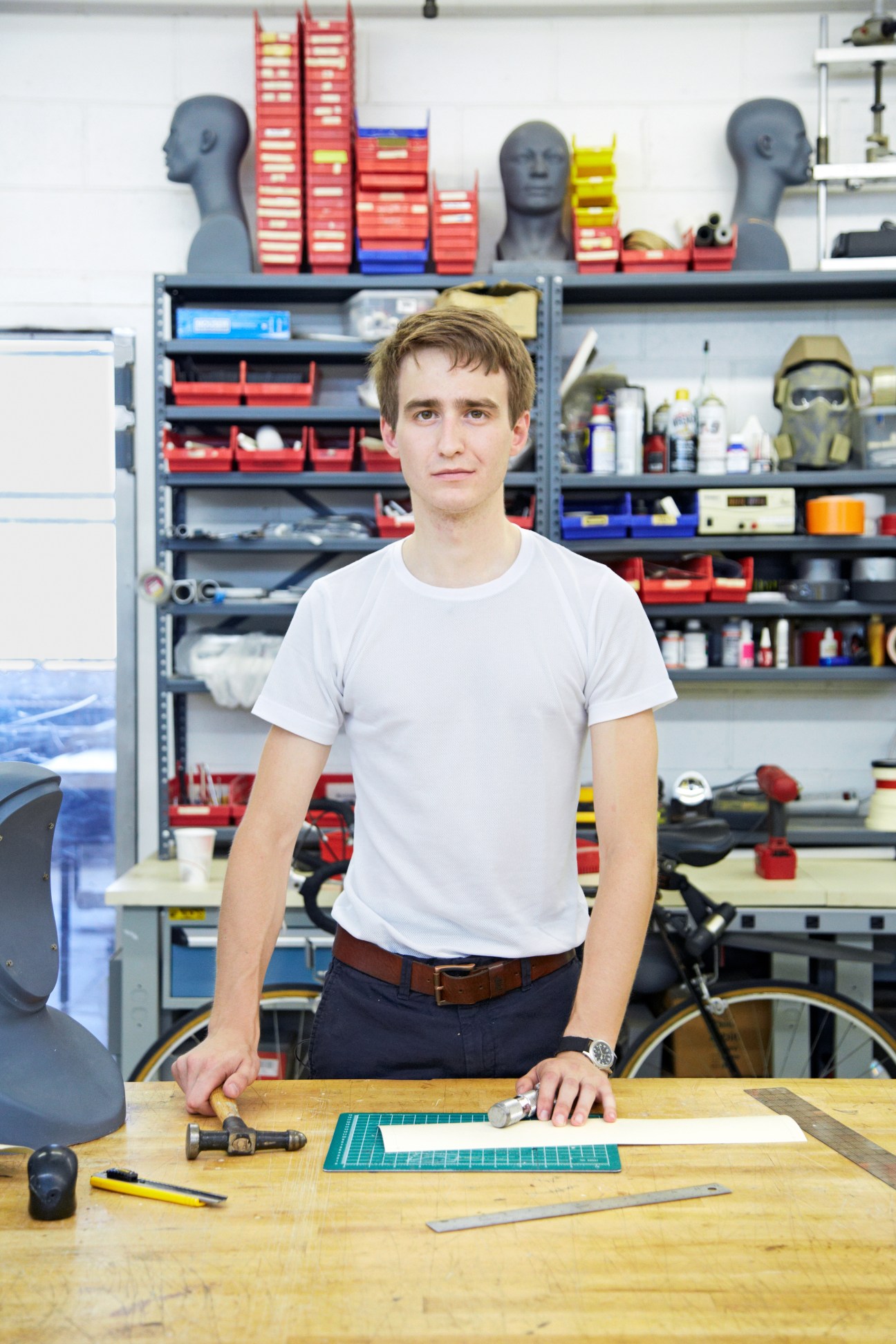 Sean Gordon, Crye Precision designer, at his workbench in Brooklyn headquarters with design tools and equipment storage behind him.